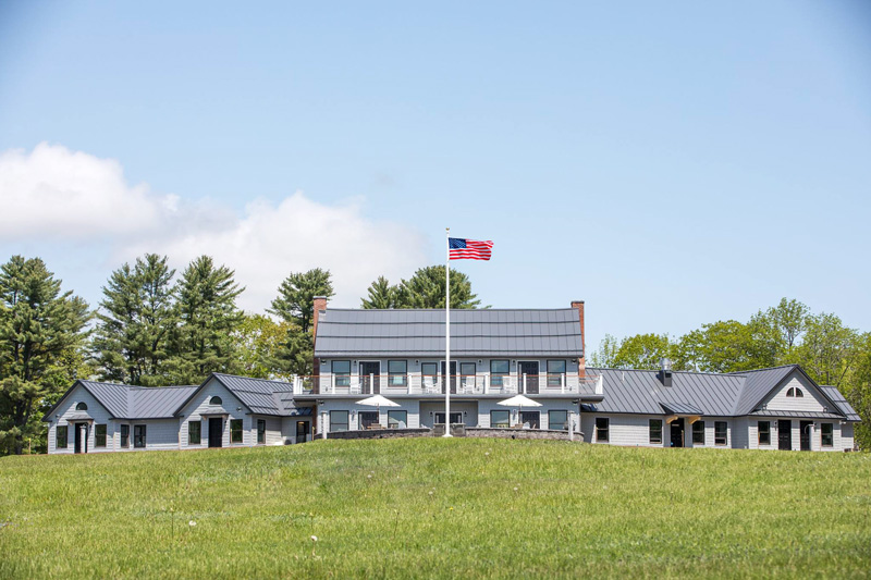 Travis-Mills-2.jpg Travis-Mills-Veterans-Retreat-Building-In-White-James-Hardie-Fiber-Cement-Siding-With-Raised-American-Flag-With-Blue-Sky-And-Puffy-White-Clouds